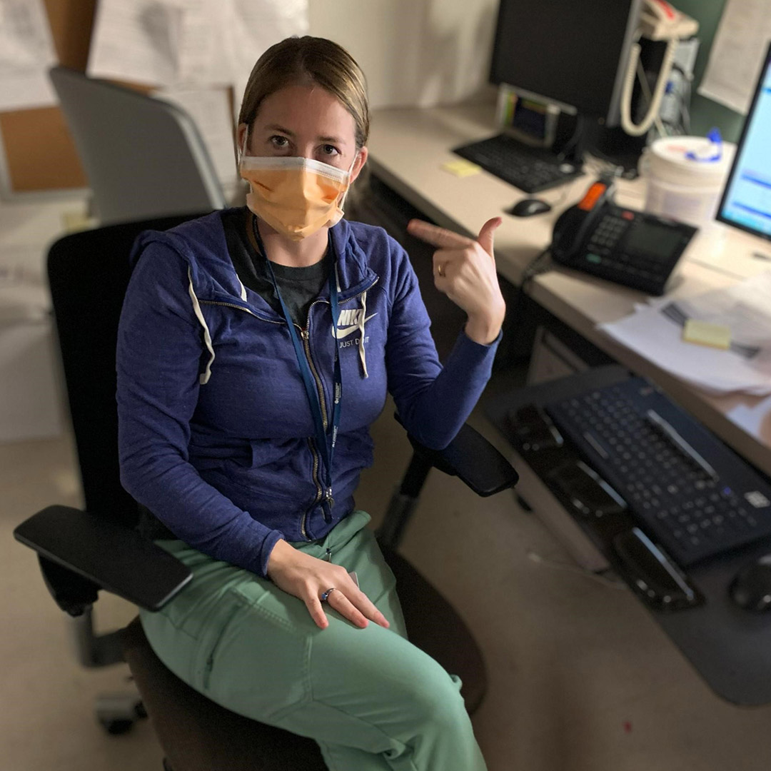 Shauna sitting at nurse's station wearing PPE in hospital