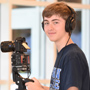 Student smiling holding camera equipment