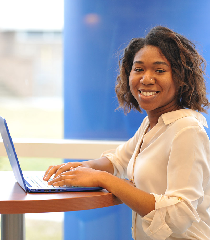 A photo of FBlessing Ike in fron of a computer where she is working on classes