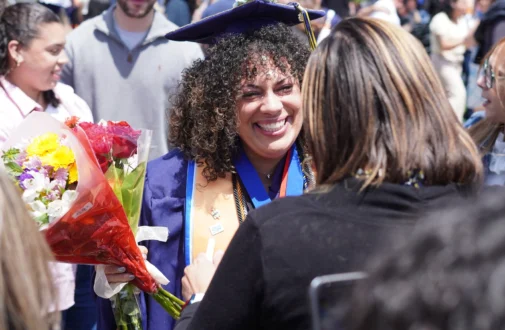 Graduate receives flowers from family and friends, celebrating graduation.