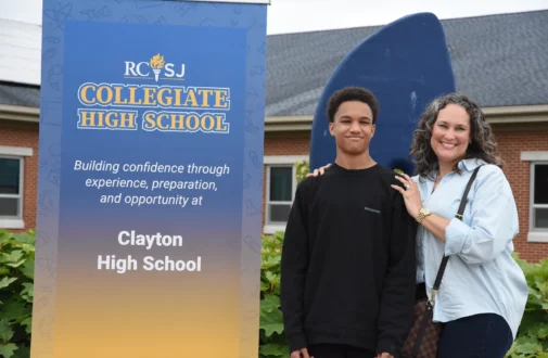 Student stands in front of a Collegiate High School sign