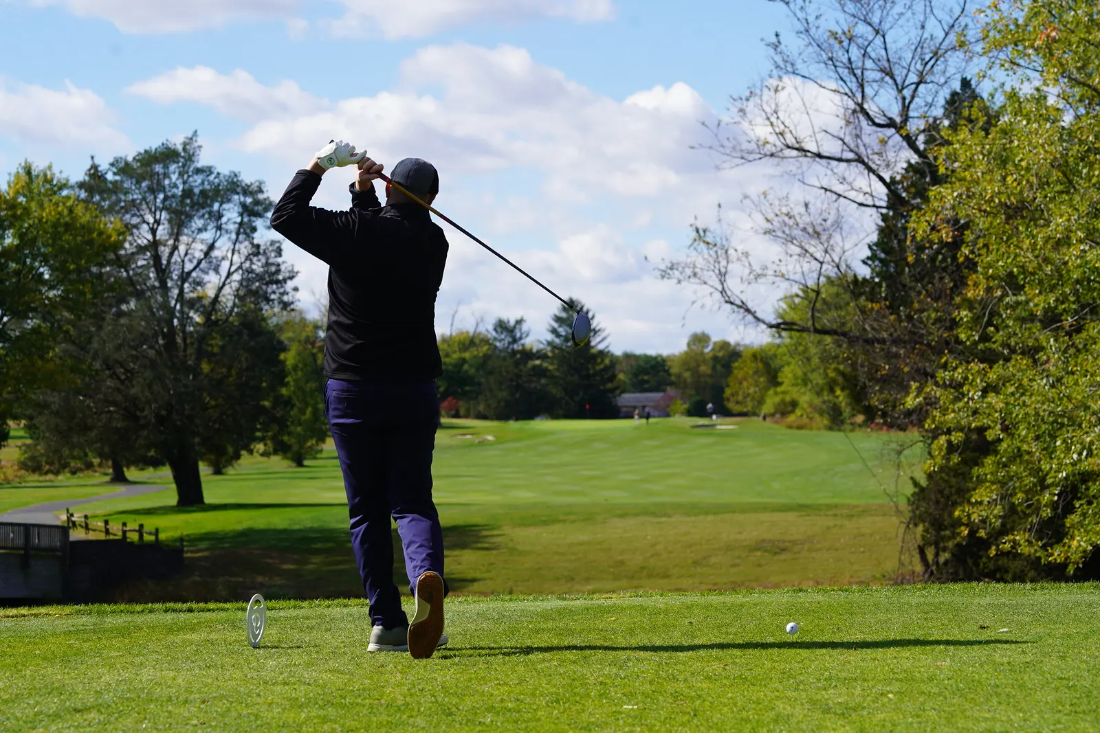 A man standing on a golf course, swinging a golf club.