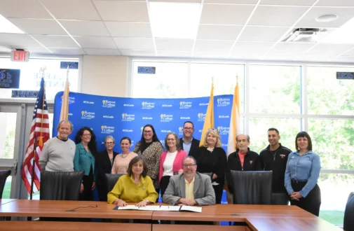 Group of individuals gathering around a table for a ceremonial endowment signing.