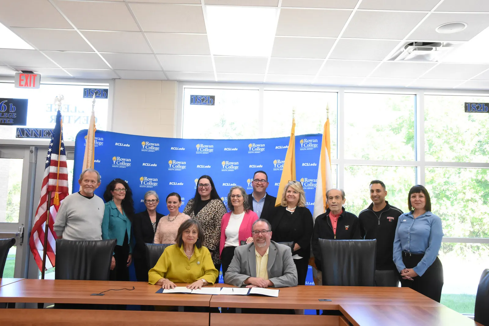 Group of individuals gathering around a table for a ceremonial endowment signing.
