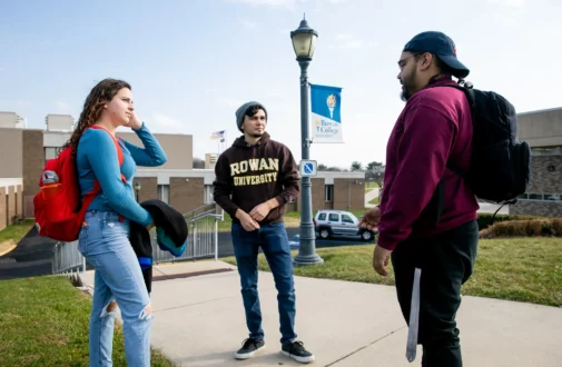 Three students stand on campus